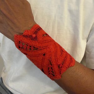 Pulseira de renda vermelha e pele de cordeiro, feita à mão em Florença, Itália. Peça única, com botão de madeira.