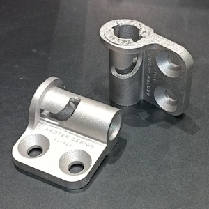 Könnte beinhalten: Zwei silberne Scharniere aus Metall mit dem Text "AROTEN DESIGN" auf der Unterseite jedes Scharniers.
