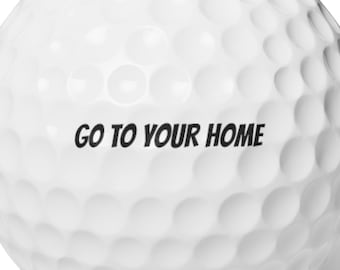 May include: A white golf ball with a dimpled surface. The text "GO TO YOUR HOME" is printed in black across the ball. The golf ball is designed for use on a golf course.