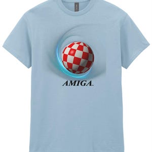 May include: A light blue t-shirt featuring a red and white chequered ball graphic and the word "AMIGA" in black text.