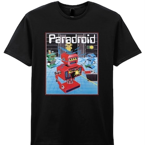 Könnte beinhalten: Schwarzes T-Shirt mit einer Retro-Grafik von Robotern in einer futuristischen Umgebung. Das Design enthält das Wort "Paradroid" in weißer, blockartiger Schrift. Die Roboter sind rot, grün, gelb und blau.