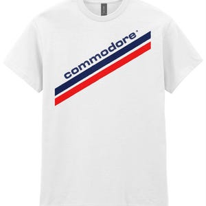 May include: White t-shirt with a diagonal red, white and blue stripe and the word "commodore" in blue letters.