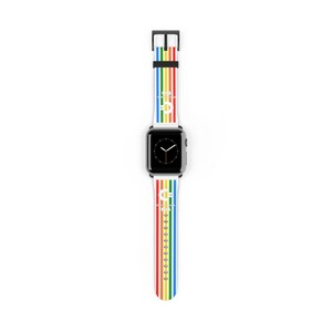 Op de afbeelding: Een witte Apple Watch met een regenboog gestreepte band. De band heeft verticale strepen in rood, oranje, geel, groen, blauw en paars. De wijzerplaat van het horloge is zwart met witte wijzers. De band heeft de tekst "CF" in het wit.