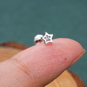 May include: A silver star-shaped stud earring with a clear crystal in the center.