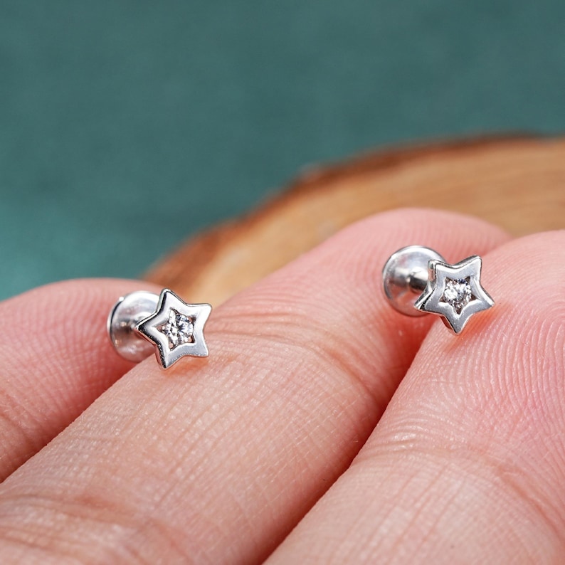 May include: A pair of silver star-shaped earrings with a small clear stone in the center of each star.