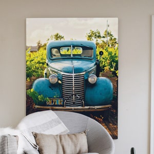 A large digital downloaded print of a vintage 1930s turquoise car hangs the wall of a modern rustic farm decor living room.  The lovely photo gives a romantic nostalgic feel to the room and contrasts wonderfully with the minimalist furniture.