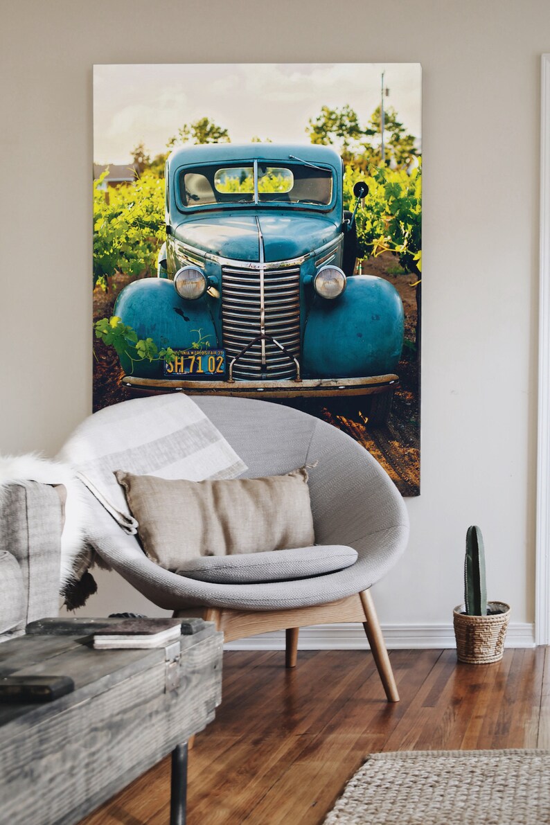 A large digital downloaded print of a vintage 1930s turquoise car hangs the wall of a modern rustic farm decor living room.  The lovely photo gives a romantic nostalgic feel to the room and contrasts wonderfully with the minimalist furniture.