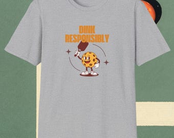 May include: A grey t-shirt with the text "DINK RESPONSIBLY" and a cartoon pickleball character holding a paddle.