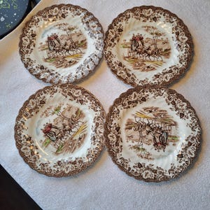 Op de afbeelding: Set van vier bruine en witte keramische dinerborden met een bloemenpatroon en een scène met een koets in het midden.