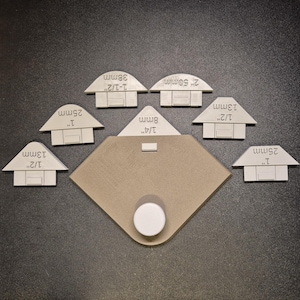May include: A set of seven white plastic corner pieces for woodworking projects. Each piece is labeled with its size in inches and millimeters. The pieces are arranged on a brown surface.