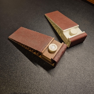 May include: Two sanding blocks with brown sandpaper and a white plastic base. Each block has a round knob on the top.