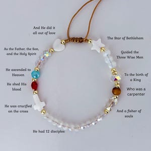 May include: A beaded bracelet with a cord closure. The bracelet features various beads in white, gold, clear, red, and blue. The bracelet includes a white cross, heart, and star-shaped beads. Text on the image reads "The Story of Jesus."