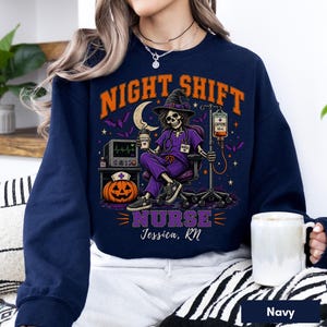 May include: A navy blue sweatshirt featuring a graphic of a skeleton nurse in a witch hat, purple scrubs, and sneakers. The design includes the text NIGHT SHIFT NURSE, a pumpkin, a heart monitor, an IV bag labeled CAFFEINE, and the name Jessica, RN.