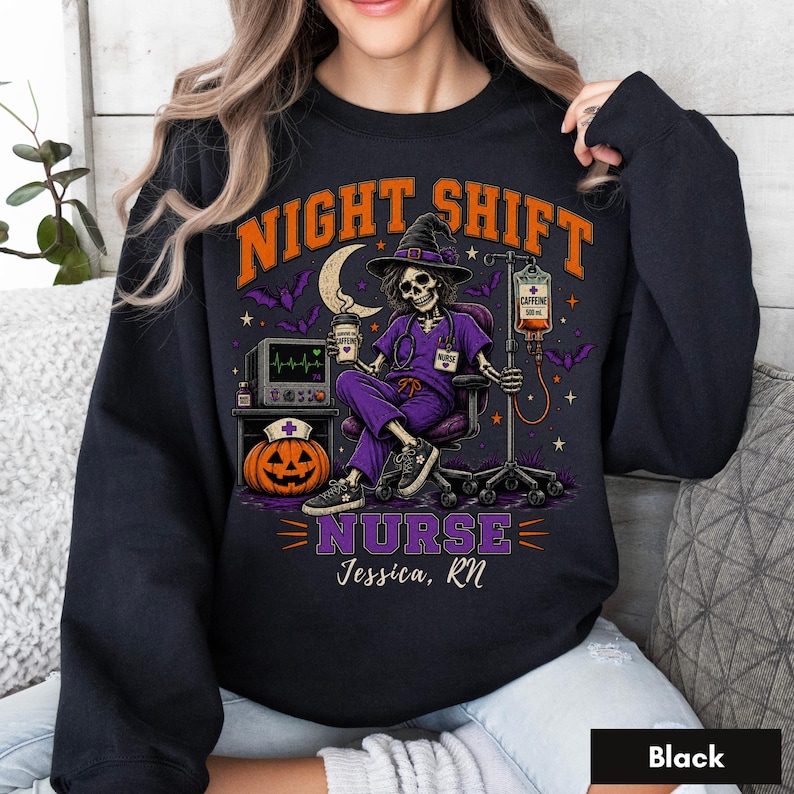 May include: A black crewneck sweatshirt featuring a graphic of a skeleton nurse in a purple scrub set and witch hat, holding a coffee cup. The design includes a pumpkin, IV drip, heart monitor, bats, and the text "NIGHT SHIFT NURSE Jessica, RN".