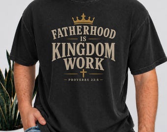 May include: Black t-shirt with the text "FATHERHOOD IS KINGDOM WORK" in a distressed, vintage style. The design includes a gold crown and cross, with "PROVERBS 22:6" below. The shirt is a dark, faded color.