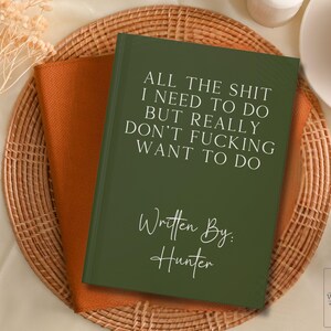 Peut inclure: Un carnet vert fonc&eacute; avec le texte "ALL THE SHIT I NEED TO DO BUT REALLY DON'T FUCKING WANT TO DO" et "Written By: Hunter" en texte blanc.