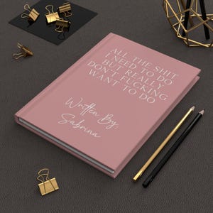 Peut inclure: Un carnet rose avec le texte "All the shit I need to do but really don't fucking want to do" et "Written By: Sabrina".