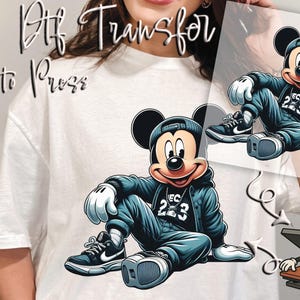 May include: DTF transfer featuring a cartoon Mickey Mouse in a blue jacket, cap, and sneakers. The image includes the text "Ready to Press" and a cartoon heat press machine. The design is suitable for apparel.