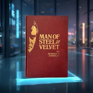Op de afbeelding: Een hardcover boek met de titel "MAN OF STEEL & VELVET" van Aubrey P. Andelin. Het boek heeft een bordeauxrode kaft met gouden letters en een gouden illustratie van een mannengezicht. Het boek staat rechtop.