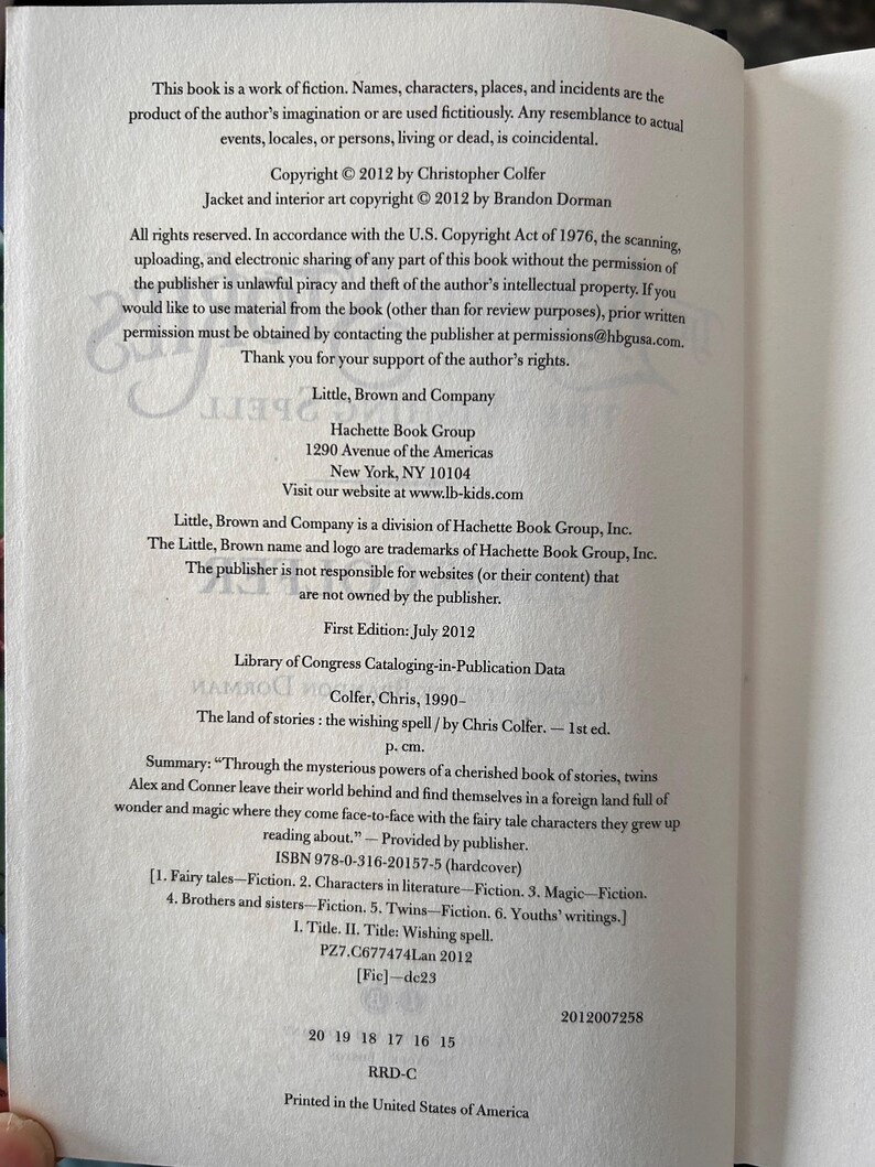 Puede incluir: P&aacute;ginas de libro abierto con texto sobre derechos de autor, informaci&oacute;n de publicaci&oacute;n y un resumen de "The Land of Stories: The Wishing Spell" de Chris Colfer. El libro tiene ISBN 978-0-316-20157-5.