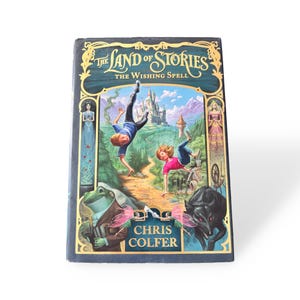 Puede incluir: Un libro de tapa dura titulado "The Land of Stories: The Wishing Spell" de Chris Colfer. La portada presenta una colorida ilustraci&oacute;n de dos ni&ntilde;os cayendo, un castillo y un lobo.