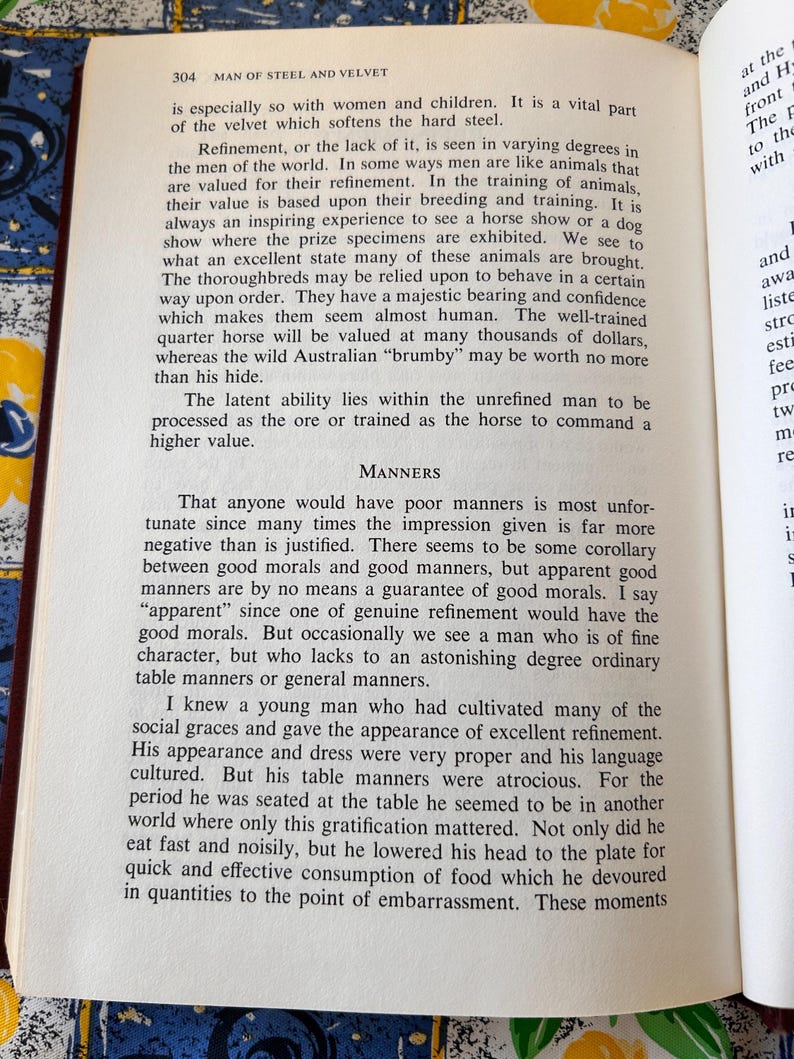 Op de afbeelding: Open boek met gedrukte tekst op een witte pagina. De tekst bevat de titel "MAN OF STEEL AND VELVET" en bespreekt verfijning en manieren. Het boek is open op een pagina met gedrukte tekst.