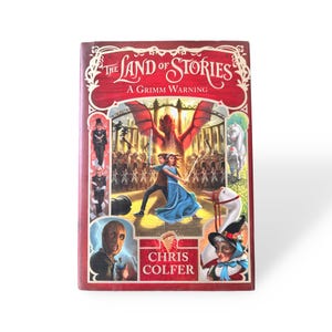 Puede incluir: Un libro de tapa dura titulado "The Land of Stories: A Grimm Warning" de Chris Colfer. La portada presenta una ilustraci&oacute;n vibrante con un drag&oacute;n rojo, una pareja bailando y otros personajes. El libro tiene un borde rojo y texto blanco.
