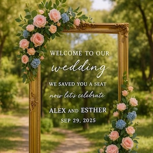 May include: A gold ornate picture frame sign featuring the text WELCOME TO OUR wedding WE SAVED YOU A SEAT now let's celebrate ALEX AND ESTHER SEP 29, 2025. The frame is decorated with pink roses, blue hydrangeas, and green leaves.