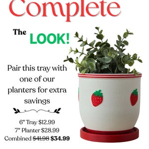 May include: A white ceramic plant pot with red trim and strawberry appliqu&eacute;s, containing a green plant. The pot sits on a matching red saucer. Text at the top reads "Complete The LOOK!"