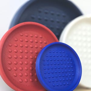 May include: A selection of round coasters in red, blue, white, and navy. Each coaster has a textured surface with small, raised bumps. The coasters are made of a durable material and are designed to protect surfaces from spills and condensation.