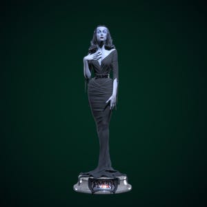 May include: A statue of a woman in a long, dark dress with a plunging neckline and a thin belt. The statue has pale skin, dark hair, and is standing on a base with the name "VAMORA" on it. The background is a dark green.