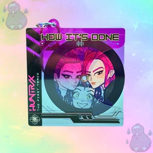 May include: A purple and black keychain featuring a vinyl record design with three illustrated faces. The text "HOW IT'S DONE" and "HUNTRAX THE FIRST TRACK" are visible. The keychain has a silver clasp.