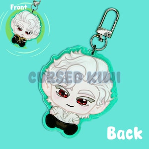 Puede incluir: Un personaje chibi blanco con ojos rojos y cabello blanco que lleva una camisa blanca y pantalones negros. El personaje está unido a un llavero plateado con un lazo plateado.