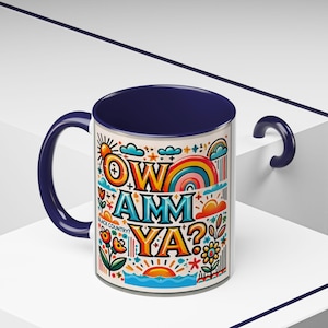 May include: A white ceramic mug with a navy blue handle and rim. The mug features a colorful graphic design with the text "OW AMM YA?" and a rainbow. The text "BLACK COUNTRY?" is also included in the design.