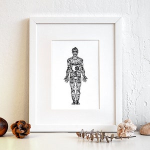 May include: A black and white line art print of a human figure with internal organs and skeletal system visible. The print is framed in a white frame and displayed on a white surface.