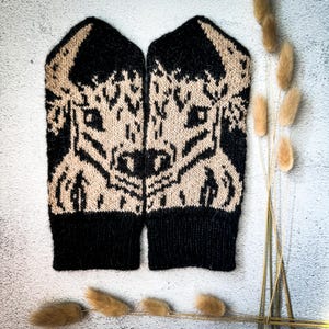 May include: A pair of black and beige knitted fingerless gloves with a bull's head design.