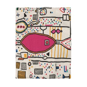May include: An off-white rectangular throw blanket with a colourful, abstract design. The pattern includes a large pink fish shape with a square centre, surrounded by geometric shapes, lines, and dots in black, yellow, blue, and red. The blanket has a textured surface.