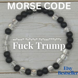 May include: A circular beaded bracelet featuring alternating black and clear beads arranged in a pattern that spells out the text "Fuck Trump" in Morse code. The bracelet is presented with the text "MORSE CODE" and "Etsy Bestseller" visible.