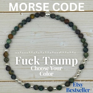 May include: A beaded bracelet with the text "MORSE CODE" at the top and "Fuck Trump" in the center. The bracelet is made of small, round, multi-colored beads and silver-colored beads. The text "Choose Your Color" is below the center text.