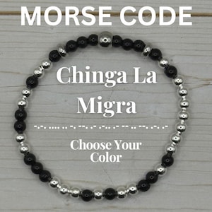 May include: A beaded bracelet with black and silver beads. The bracelet has the words "Chinga La Migra" in the center, with "MORSE CODE" above and "Choose Your Color" below. Morse code symbols are also present.