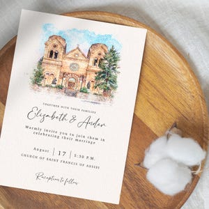 以下が含まれることがあります： 水彩画風の結婚式の招待状。教会が描かれています。招待状には「Elizabeth & Ander」の名前、8月17日の日付、午後5時30分の時間が含まれています。「Church of Saint Francis of Assisi」の文字も表示されています。