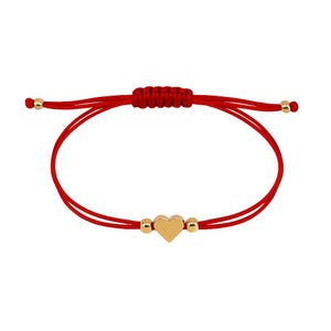 Puede incluir: Pulsera de hilo rojo con un dije de corazón dorado y cuentas doradas. La pulsera es ajustable con un cierre de nudo corredizo. El dije de corazón está centrado.
