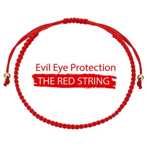 May include: A red string bracelet with gold-colored beads at the ends. The bracelet features the text "Evil Eye Protection" and "THE RED STRING" in white letters on a white background.