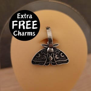 May include: A silver body piercing with a dangling charm in the shape of a moth with crescent moons and stars. The charm is attached to a silver ring. The text "Extra FREE Charms" is visible in the background.