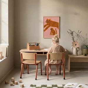 K&ouml;nnte beinhalten: Ein Kind sitzt an einem Holztisch mit zwei passenden St&uuml;hlen. Ein gerahmter rosa Druck mit einem Leopardenmuster h&auml;ngt an der Wand. Eine Holzkiste enth&auml;lt Buntstifte. Ein gr&uuml;n-wei&szlig; karierter Teppich liegt auf dem Boden.