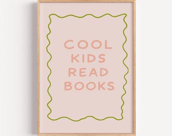 May include: A framed print featuring the words "COOL KIDS READ BOOKS" in pink on a pale pink backdrop. A wavy green border surrounds the text. The frame is a light brown colour.