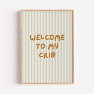 Puede incluir: Una impresión enmarcada con un fondo a rayas gris claro y blanco. El texto "WELCOME TO MY CRIB" está escrito en marrón, con una fuente de letra manuscrita.