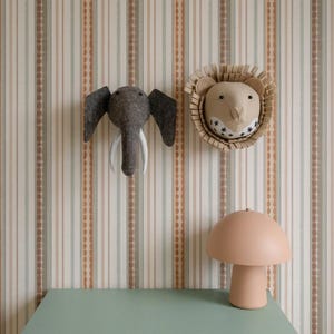 May include: A whimsical nursery scene featuring an elephant and lion head wall decor, and a mushroom-shaped lamp on a green cabinet. The wallpaper has vertical stripes in neutral tones.