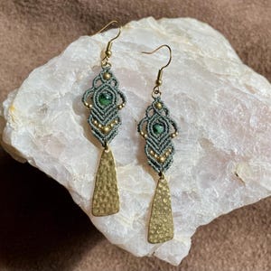 May include: A pair of grey macrame earrings with green stone accents and hammered gold teardrop dangles.