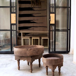 Può includere: Due tavolini antichi in legno con piani rotondi e gambe scolpite. I tavoli sono realizzati in legno dai toni caldi e hanno un aspetto rustico e invecchiato. Il tavolo più grande ha un diametro di circa 61 cm, e il tavolo più piccolo circa 46 cm.